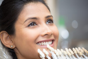 Woman smiling with inlays held up to her teeth